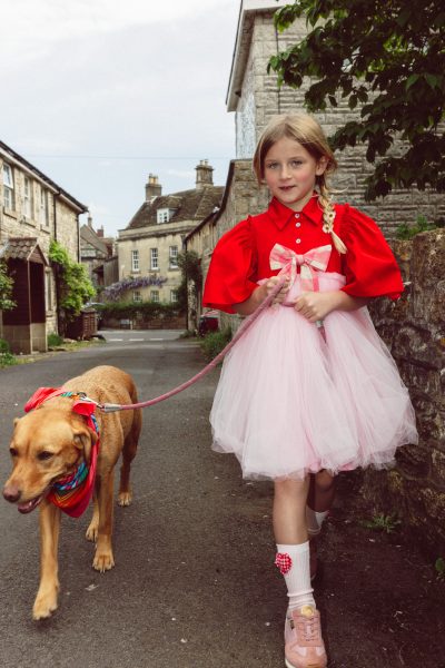Flossy porte une robe Christina Rohde, un nœud Bebe Organic, des chaussettes Zara et des baskets Young Soles. Thandie, le labrador de couleur rousse, porte un foulard Lorna Murray. - Doolittle