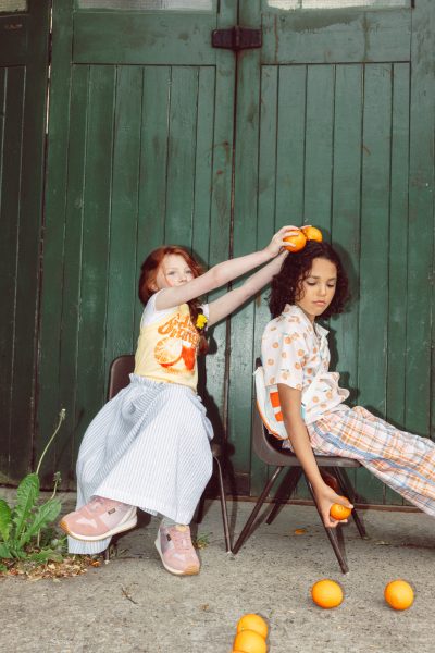 Bea porte une jupe Tangerine, un gilet et des chaussettes Zara, un chapeau bob Ki ET LA et des baskets Young Soles. Remy porte une chemise et un pantalon The Sunday Collective, un sac banane Ki ET LA et des baskets Young Soles - Doolittle