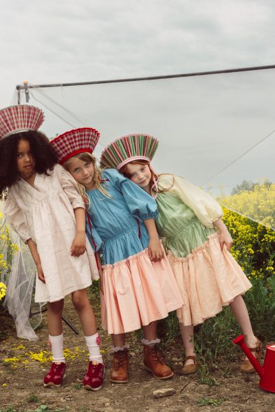 Juliet porte une robe Kenzo, un chapeau Lorna Murray, des chaussettes Zara et des baskets Young Soles. Flossy et Bea portent des robes The Middle Daughter, des chapeaux Lorna Murray ainsi que des bottines et des chaussures Young Soles. - Doolittle