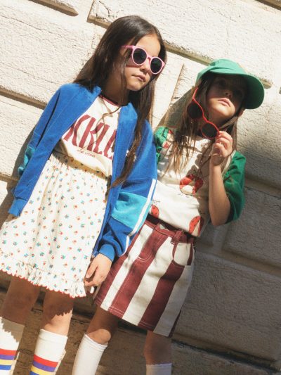 Laura : Casquette Bobo Choses, Jupe Wynken, T-shirt & top The Campamento, Anna Emy : T-shirt Bobo Choses, veste et jupe The Campamento, chaussettes Wynken  - Doolittle